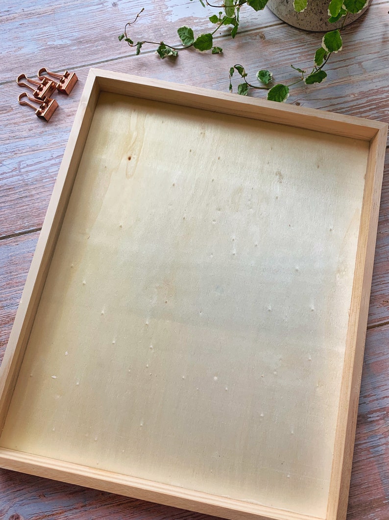 May include: A natural wood frame with a light wood-toned background. The frame is empty and ready for a picture or artwork.