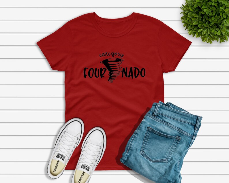May include: Red t-shirt with a black graphic of a tornado and the text "category four NADO". The shirt is laying on a white wooden surface with a pair of white sneakers and blue jeans.