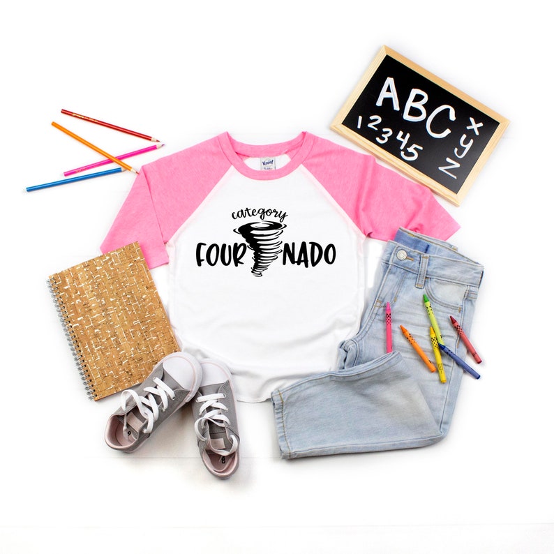 May include: White and pink baseball tee shirt with a black graphic of a tornado with the text "category four-nado".