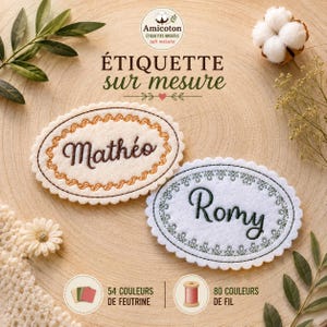Peut inclure: Deux étiquettes ovales en feutrine aux bords festonnés. Une étiquette crème avec une broderie marron indiquant Mathéo, et une blanche avec une broderie vert foncé indiquant Romy. Texte inclus : Amicoton, Étiquette sur mesure, 54 couleurs de feutrine, 80 couleurs de fil.