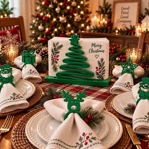 Może przedstawiać: Zielony metalowy serwetnik w kształcie choinki z gwiazdą na szczycie, zawierający białe serwetki z nadrukiem Merry Christmas i motywami roślinnymi. Cztery zielone pierścienie na serwetki w kształcie renifera, bałwana i prezentu.