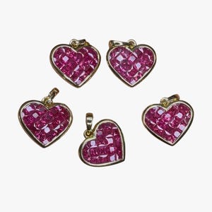 Puede incluir: Cinco colgantes de corazón de oro con piedras de rubí rojo. Cada colgante está engastado con un racimo de rubíes de talla cuadrada.