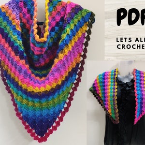 Puede incluir: Un chal de ganchillo colorido con un borde festoneado. El chal está hecho con una variedad de colores, incluyendo rosa, morado, azul, verde y amarillo. El chal se muestra en un maniquí que lleva una camisa negra.