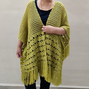 Puede incluir: Un poncho de crochet verde lima con flecos. El poncho tiene un corte holgado y está abierto en la parte delantera.