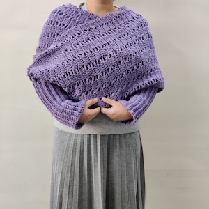 Puede incluir: Un suéter de ganchillo morado de corte holgado y mangas largas. El suéter tiene un delicado patrón de calado y cuello en V.