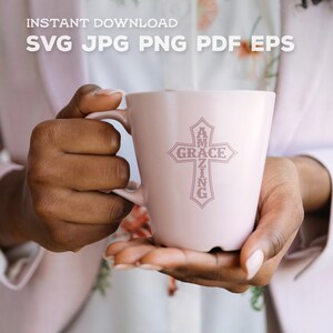 May include: A pink ceramic mug with a cross design. The cross is made up of the words "Amazing Grace".