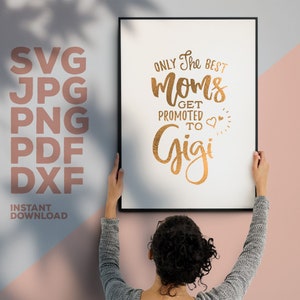 Może przedstawiać: Wydruk w ramie ze złotym napisem "Only the best moms get promoted to Gigi" z dwoma małymi sercami i grafiką słońca. Wydruk wisi na r&oacute;żowej ścianie.
