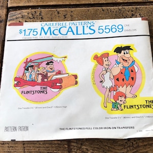 Puede incluir: Un patrón de transferencia de planchado vintage de McCall's con los Picapiedra. El patrón incluye dos transferencias, una de la familia Picapiedra en su coche y otra de Fred Picapiedra y Pebbles. El patrón está etiquetado como "Carefree Patterns from McCall's 5569".