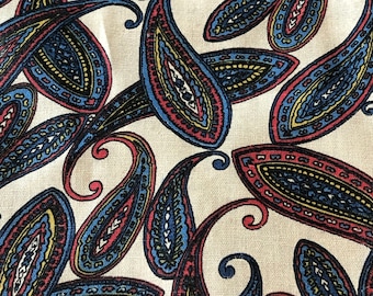 May include: A fabric with a paisley pattern in shades of blue, red, yellow, and black on a cream background.