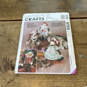 Puede incluir: Un patrón de costura para hacer muñecas con botones. El patrón incluye tres diseños de muñecas diferentes, cada uno con un atuendo y accesorios únicos. El patrón es de McCall's Crafts y está numerado 6725.
