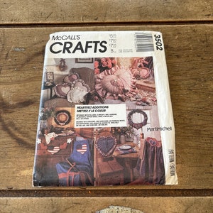 May include: McCall's Crafts sewing pattern 3502 for heart-felt additions. The pattern includes instructions for making pillows, wreaths, wall hangings, placemats, napkin rings, and a necklace. The pattern cover features a variety of heart-shaped crafts in red, white, and blue.