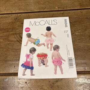 Puede incluir: Un patrón de costura McCall's para bragas de bebé. El patrón presenta múltiples bragas de bebé en varios estilos, incluyendo diseños con volantes y lazos. El patrón está etiquetado como "Easy" e incluye el número M6345.
