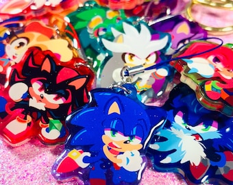 Könnte beinhalten: Eine Sammlung bunter Schlüsselanhänger mit Comicfiguren, darunter Sonic the Hedgehog, Shadow the Hedgehog und Silver the Hedgehog. Die Schlüsselanhänger bestehen aus klarem Acryl mit eingearbeitetem Glitzer.
