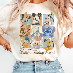May include: Ivory t-shirt with a grid design showcasing Disney characters such as Mickey Mouse, Minnie Mouse, Donald Duck, and Stitch. The words "Walt Disney World" are printed below in a script font.