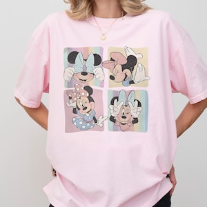 Puede incluir: Camiseta rosa claro con un dise&ntilde;o de cuatro paneles de Minnie Mouse. Cada panel muestra a Minnie en una pose y atuendo diferente, con lazos de varios colores. La camiseta es de corte holgado.