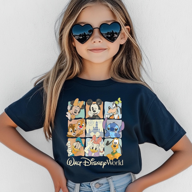 Peut inclure: T-shirt bleu marine avec une grille de personnages Disney, dont Mickey Mouse, Minnie Mouse et Dingo. Le texte "Walt Disney World" est imprim&eacute; en blanc en bas.