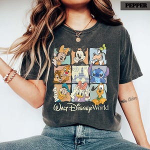 May include: Dark grey t-shirt with a grid of Disney characters: Mickey, Minnie, Goofy, Donald, Daisy, Chip and Dale, Stitch, and Pluto. The words "Walt Disney World" are printed below the grid in white.
