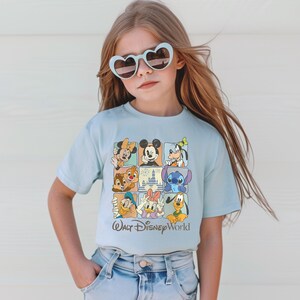 Peut inclure: Un t-shirt bleu clair avec une grille de personnages Disney, dont Mickey Mouse, Minnie Mouse, Donald Duck et Stitch. Le t-shirt porte l'inscription "Walt Disney World" en dessous. La personne porte des lunettes de soleil en forme de c&oelig;ur.