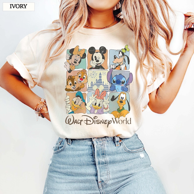 May include: Ivory t-shirt with a grid design showcasing Disney characters such as Mickey Mouse, Minnie Mouse, Donald Duck, and Stitch. The words "Walt Disney World" are printed below in a script font.