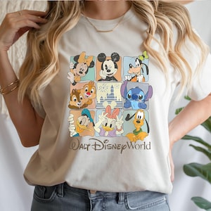 Peut inclure: Un t-shirt cr&egrave;me avec une grille de neuf carr&eacute;s, chacun pr&eacute;sentant un personnage Disney diff&eacute;rent, dont Mickey Mouse, Minnie Mouse et Dingo. Les mots "Walt Disney World" sont imprim&eacute;s dans une police stylis&eacute;e en dessous de la grille.