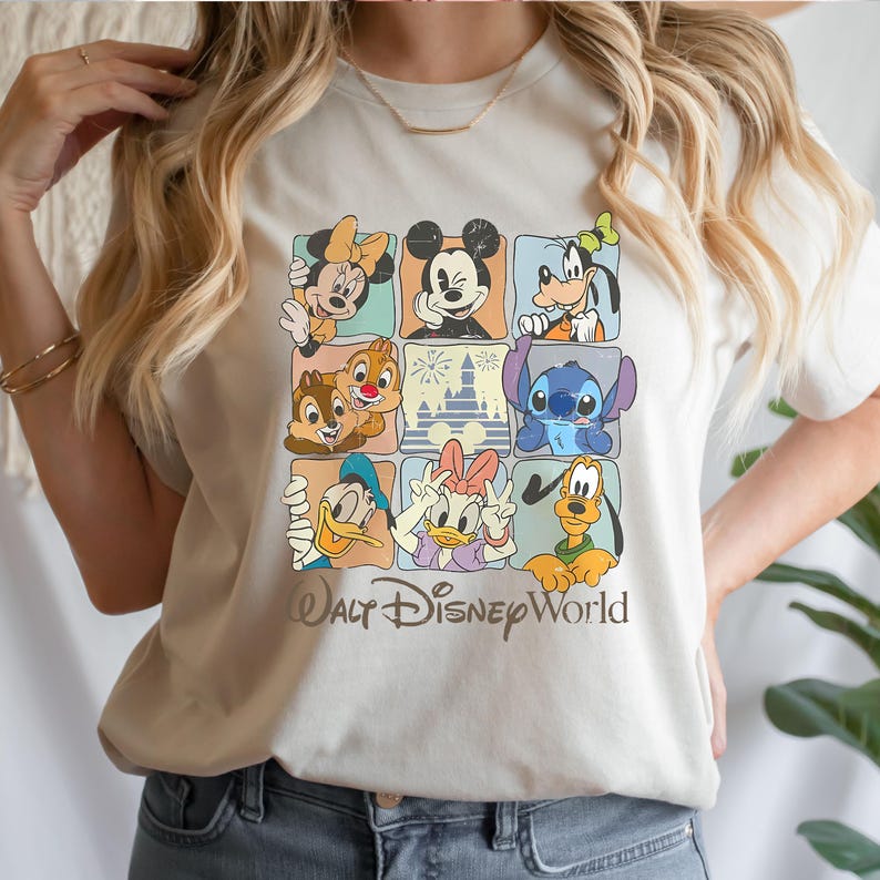 Peut inclure: Un t-shirt cr&egrave;me avec une grille de neuf carr&eacute;s, chacun pr&eacute;sentant un personnage Disney diff&eacute;rent, dont Mickey Mouse, Minnie Mouse et Dingo. Les mots "Walt Disney World" sont imprim&eacute;s dans une police stylis&eacute;e en dessous de la grille.
