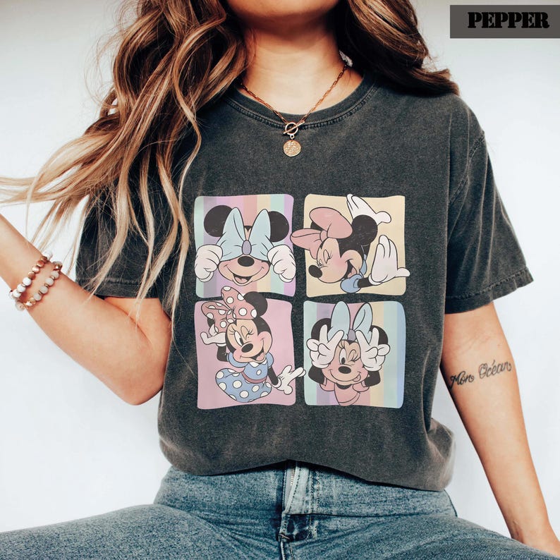 Puede incluir: Camiseta gris oscuro con un dise&ntilde;o de cuatro paneles de Minnie Mouse en varias poses. Cada panel tiene un fondo de arco&iacute;ris pastel. La camiseta tiene un aspecto vintage y desgastado.