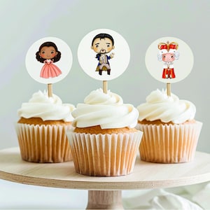 May include: Three cupcakes with white frosting and different character toppers. The toppers are a cartoon of a woman in a pink dress, a man in a blue jacket, and a woman in a crown and white dress.