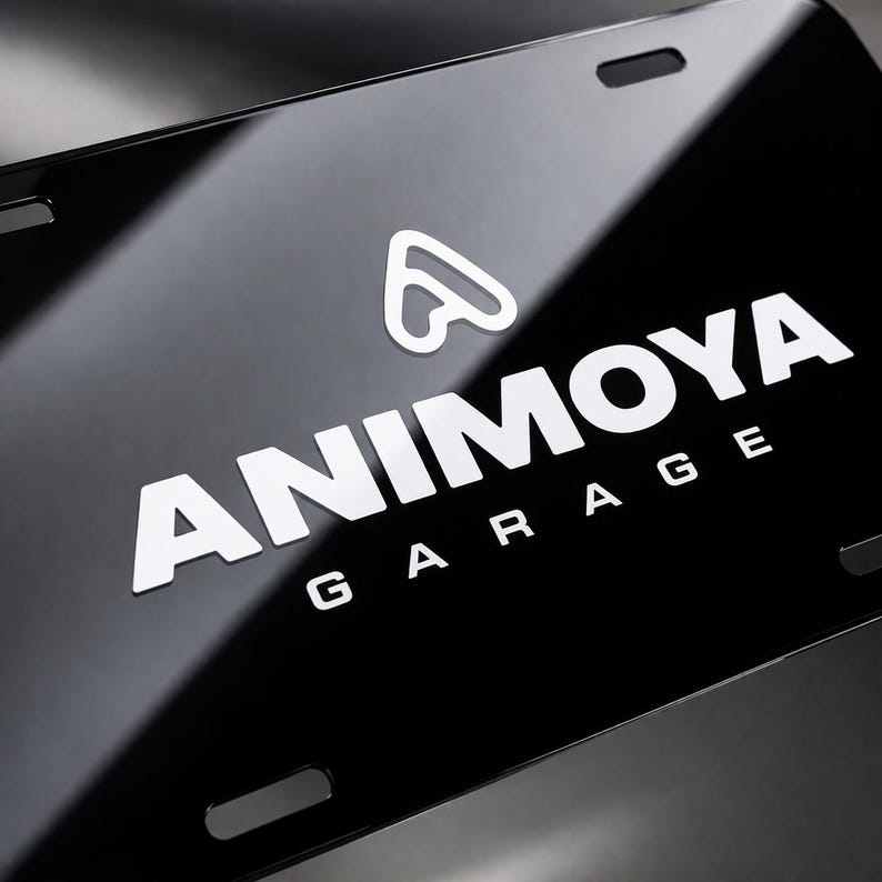 以下が含まれることがあります： 白い文字で「ANIMOYA GARAGE」と白いロゴが入った光沢のある黒いナンバープレート。 プレートには4つの取り付け穴があり、反射面があります。