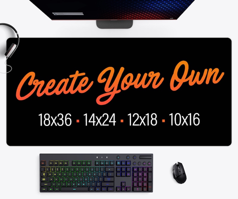 May include: Black desk mat with the text "Create Your Own" in orange and yellow script. The mat has size options: 18x36, 14x24, 12x18, and 10x16 inches. A keyboard, mouse, and headphones are also visible.
