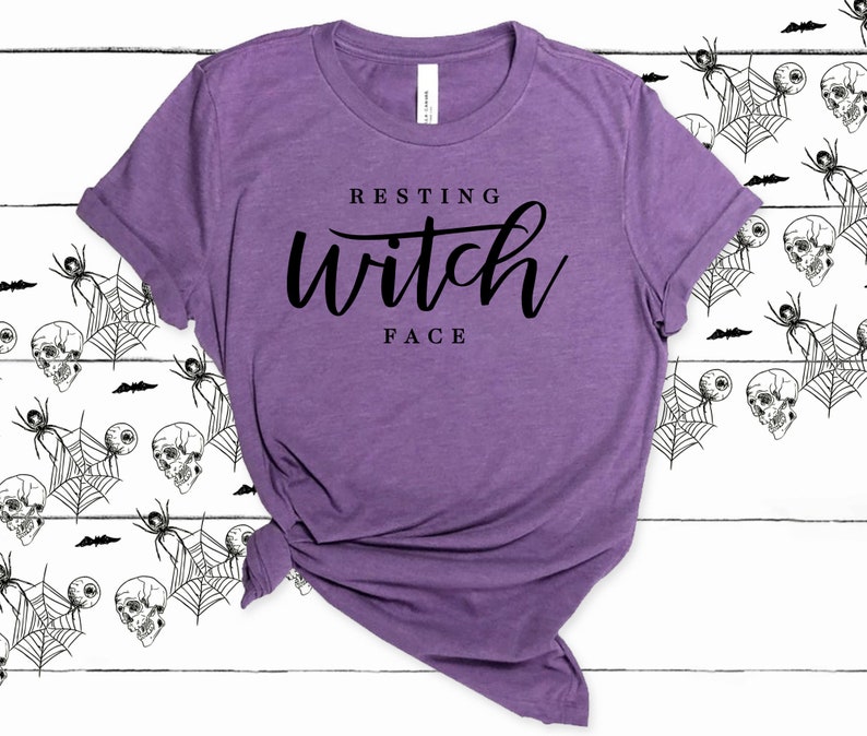 May include: Purple t-shirt with the text "Resting Witch Face" in black lettering.