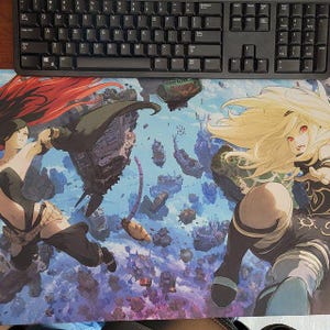 May include: A black computer keyboard rests above a colorful mousepad featuring an anime-style illustration. The mousepad depicts two female characters with long hair, set against a backdrop of floating islands and a blue sky.