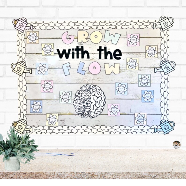 May include: A classroom noticeboard with a wooden background and a white border. The noticeboard has a floral theme with the words "Grow with the Flow" in black letters. There are several colourful flowers and watering cans on the board.