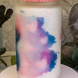 May include: A white glass jar with a pink lid and a blue and pink watercolor design with pink hearts.