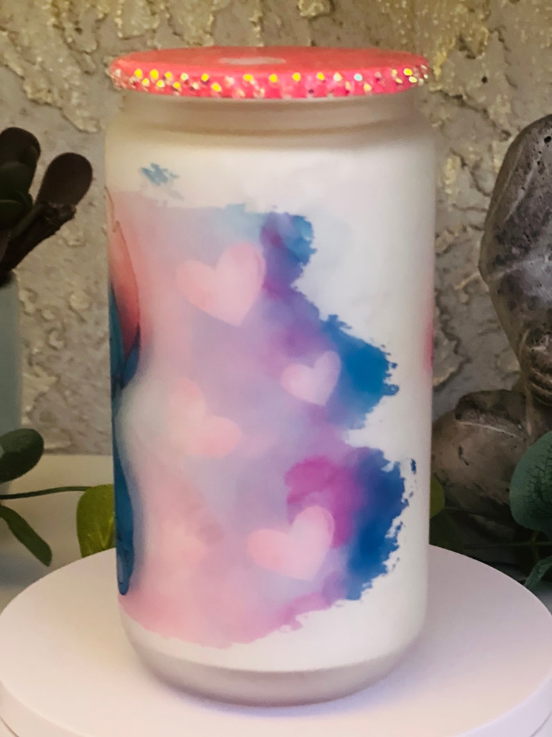 May include: A white glass jar with a pink lid and a blue and pink watercolor design with pink hearts.