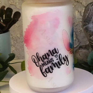 May include: White ceramic jar with a pink and blue watercolor design. The jar has a pink glitter lid and features the text "Ohana means family" in black lettering.