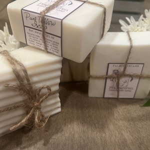 May include: Three bars of handmade soap wrapped in twine. The soap is white and has a label that says "Pure Tallow Soap" and "Paleo Skincare".