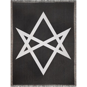 May include: Black throw blanket with a white geometric star design. The blanket has a fringed edge and a woven texture. The star is composed of intersecting triangles and lines, creating a symmetrical pattern.