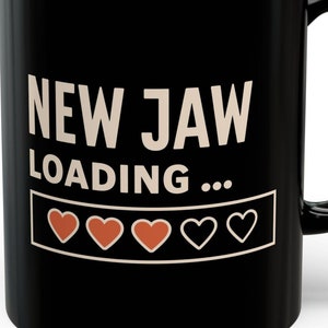 Puede incluir: Taza de café negra con el texto "NEW JAW LOADING..." y una barra de progreso de cinco corazones, cuatro de los cuales están llenos de rojo.