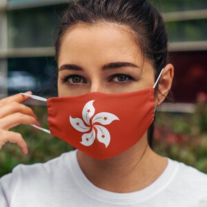 Op de afbeelding: Een vrouw draagt ​​een rood gezichtsmasker met de vlag van Hongkong erop gedrukt. Het masker heeft een wit bauhinia-bloemmotief.