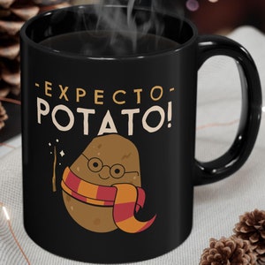 Pode incluir: Caneca de cerâmica preta com um gráfico branco de uma batata usando óculos e uma echarpe. O texto "Expectro Potato!" está impresso na caneca.