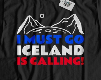 Könnte beinhalten: Schwarzes T-Shirt mit einer weißen Grafik von Bergen und dem Text "I MUST GO ICELAND IS CALLING!" in Blau, Rot und Weiß.