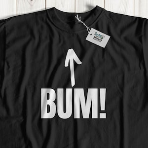 May include: Black t-shirt with a white arrow pointing up and the word "BUM!" printed on the front.