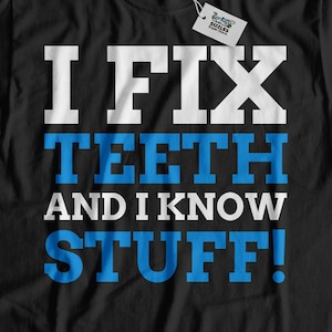 May include: Black t-shirt with white text that reads "I FIX TEETH AND I KNOW STUFF!" The text is in a bold, blocky font. The shirt is on a white wood background.