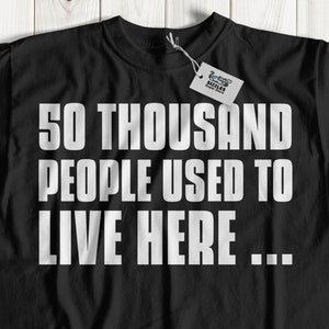Puede incluir: Camiseta negra con texto blanco que dice "50 mil personas solían vivir aquí..."