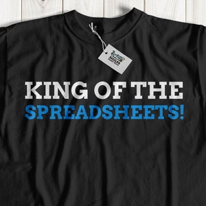 Może przedstawiać: Czarny T-shirt z białym tekstem, który brzmi "KING OF THE SPREADSHEETS!" w niebieskich literach.