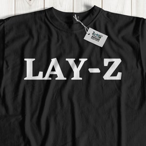 May include: Black t-shirt with white text that reads "LAY-Z".