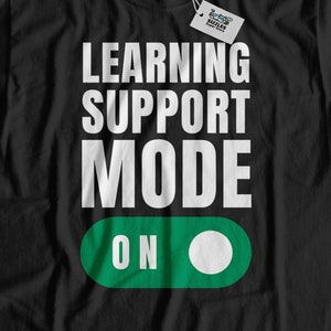 Puede incluir: Camiseta negra con texto blanco que dice "Learning Support Mode On" con un gráfico de interruptor de palanca verde y blanco.