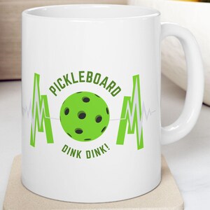 May include: White ceramic mug with a green pickleball and the text "Pickleboard Dink Dink!" in a green heartbeat graphic.