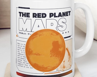 Op de afbeelding: Een witte keramische mok met een zwart en oranje ontwerp met de tekst "THE RED PLANET MARS" en een afbeelding van de planeet Mars. De tekst "プラネット・アー" staat ook op de mok.