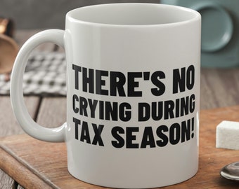 May include: White ceramic coffee mug with a black inscription that reads "There's no crying during tax season!"